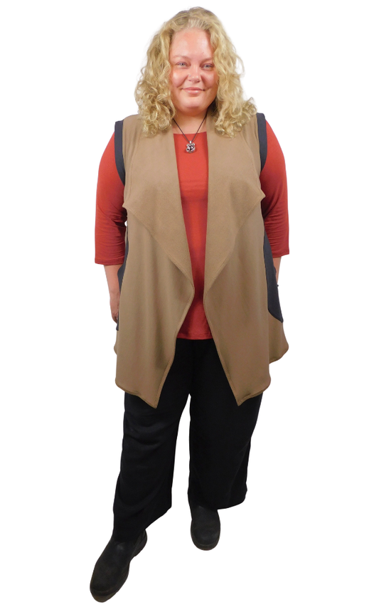 Woman wearing a beige vest over a red shirt with black pants on a white background