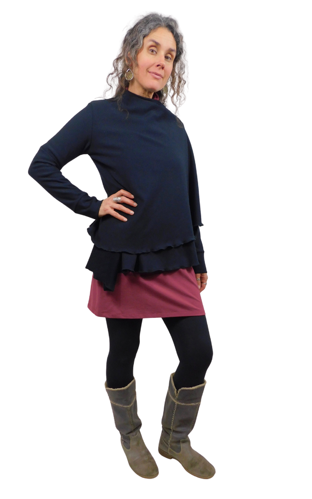 Woman wearing a black top and wine coloured skirt with black tights and gray boots on a white background
