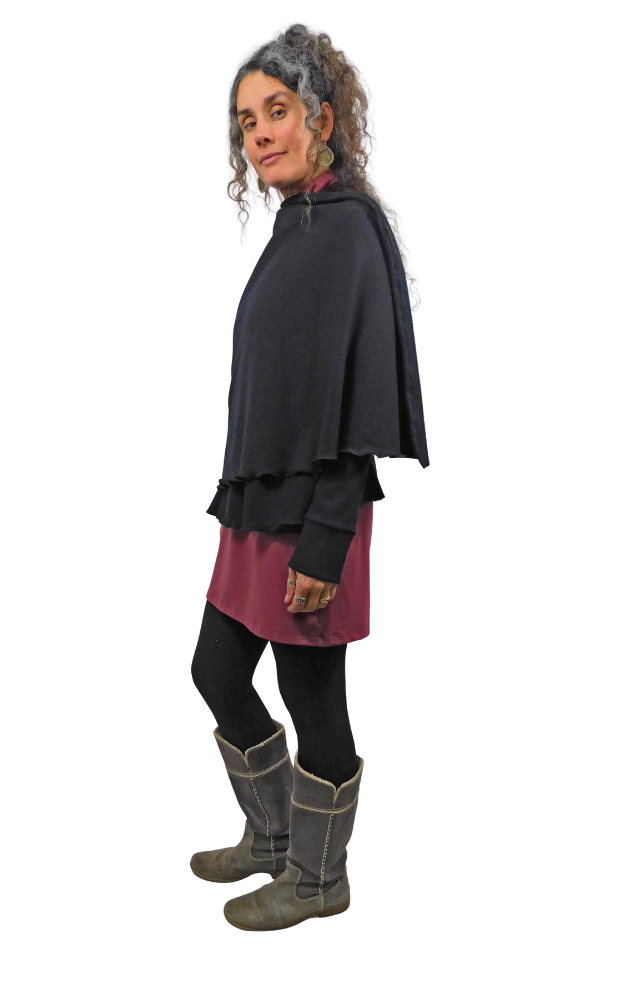 Woman wearing a black layered outfit with a wine coloured skirt and gray boots on a white background