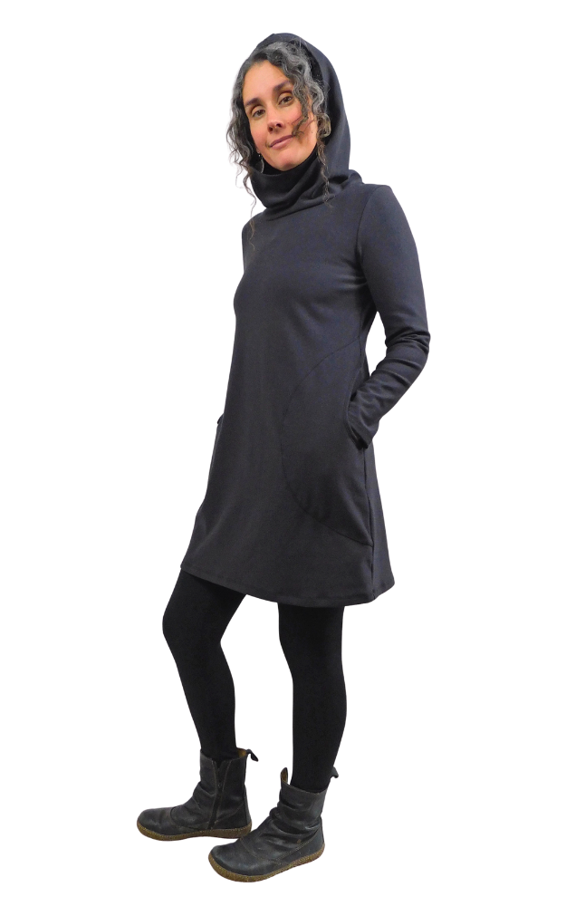 Woman wearing a black hooded tunic with long sleeves and hands in pockets