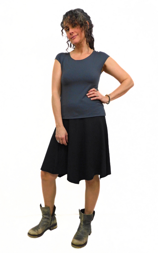 Woman standing in pose one hand on hip wearing graphite grey top and black skirt