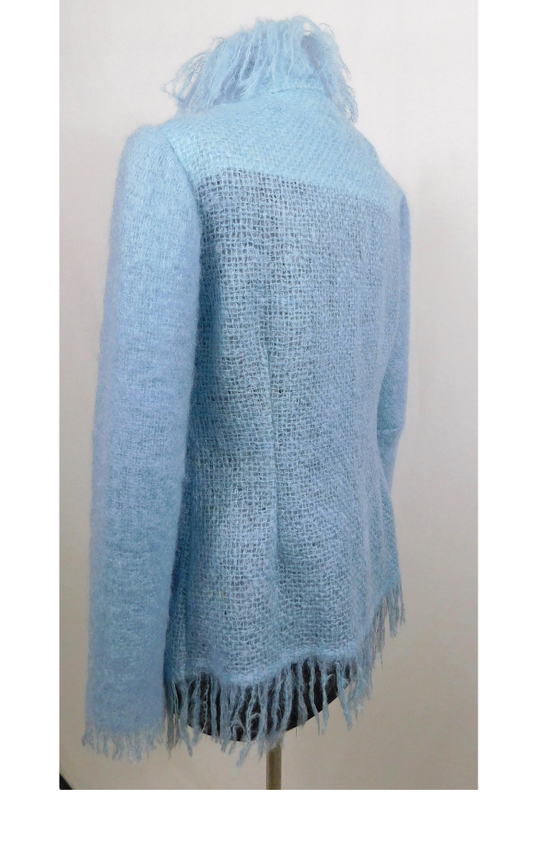 Light blue knitted jacket with fringe on a mannequin against a white background