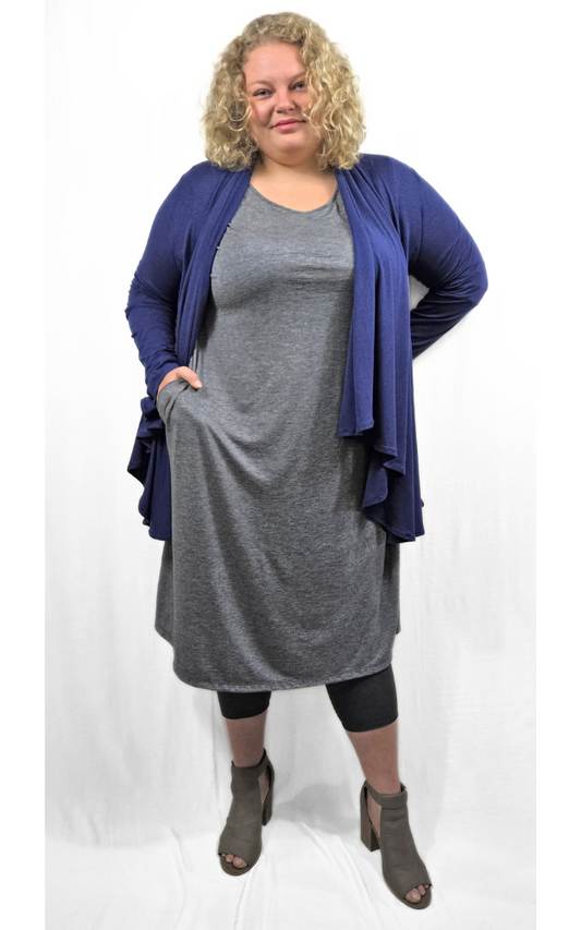 Plus size model standing wearing long charcoal dress and blue wrap cardigan