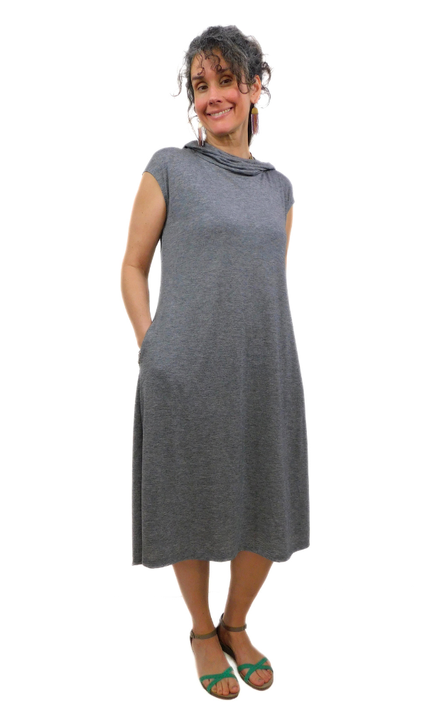 Woman standing with hands in pocket wearing lightweight charcoal tunic long dress with loose hood worn down around neck