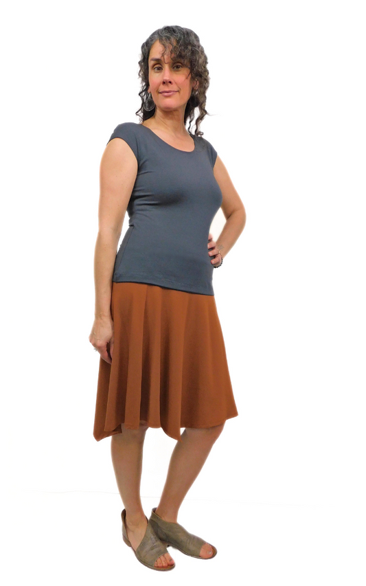 Woman standing in pose wearing graphite grey top and toffee brown skirt