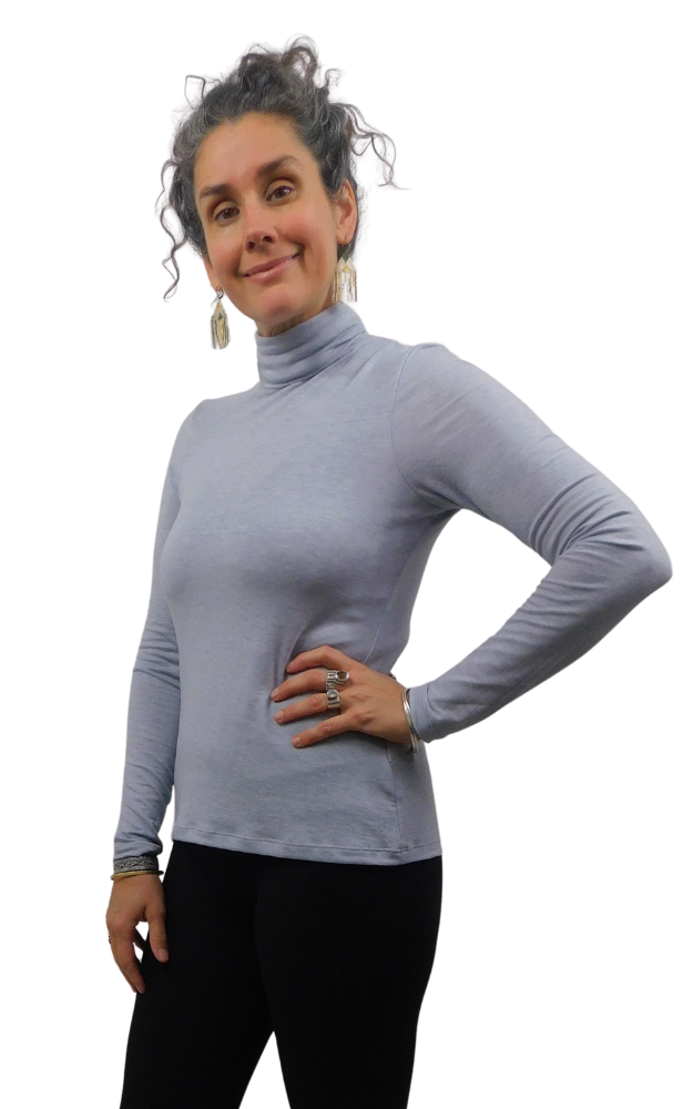 Woman wearing a grey turtle neck sweater with long sleeves and holding one hand on hip