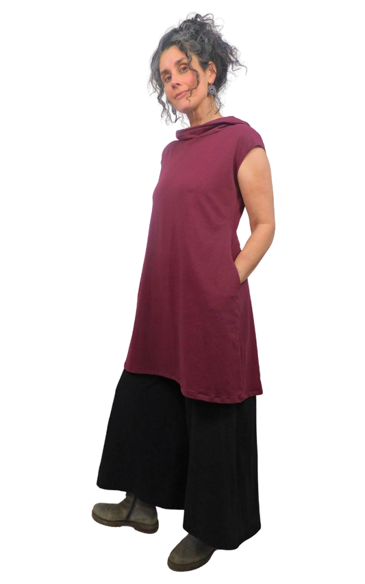 Woman wearing a burgundy sleeveless top and black pants on a white background