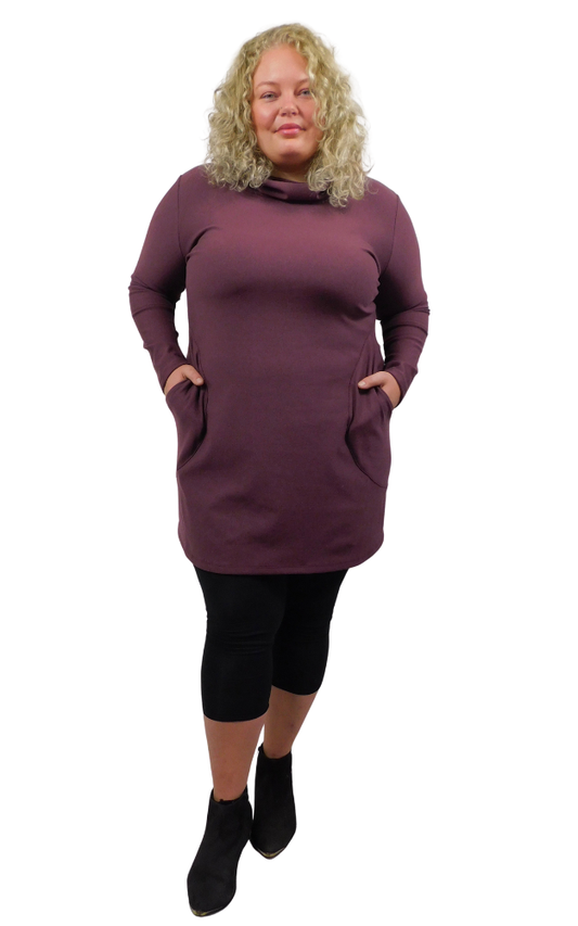 Woman wearing a long purple dress with pockets on a white background