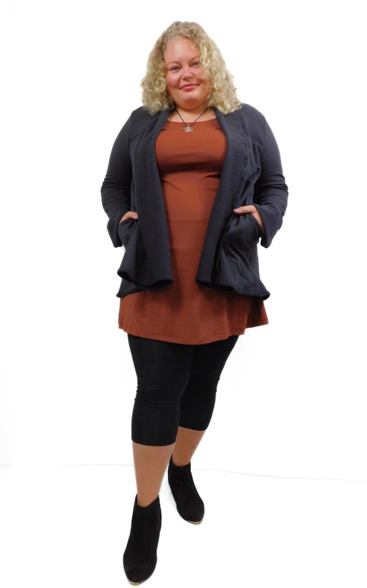 Woman wearing a brown dress with a black fleece cardigan on a white background