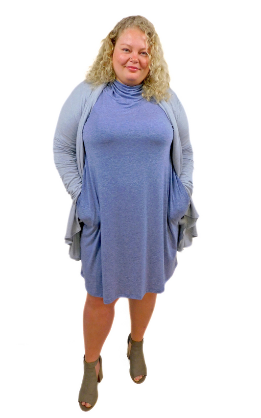 Plus sized woman wearing blue dress with hands in pockets and grey wrap cardigan