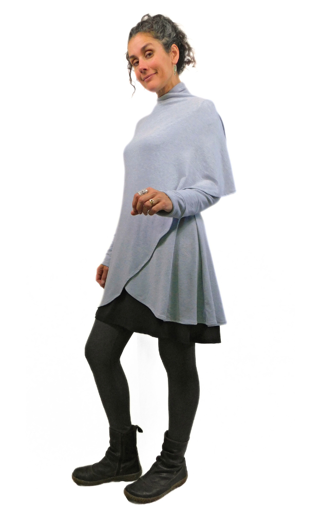 Woman standing with one arm showing wearing long grey cardigan that wraps around one shoulder