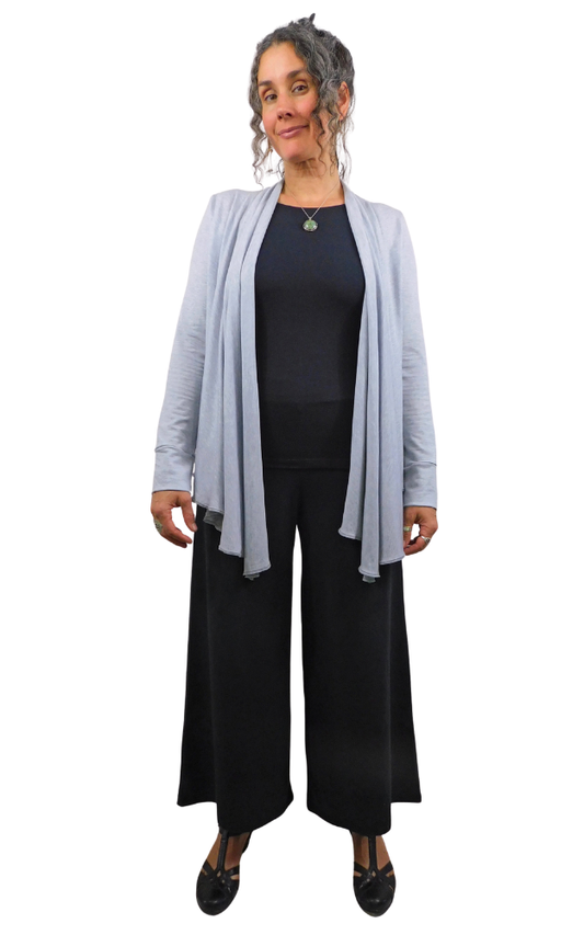 Woman wearing a light gray cardigan over a black outfit on a white background