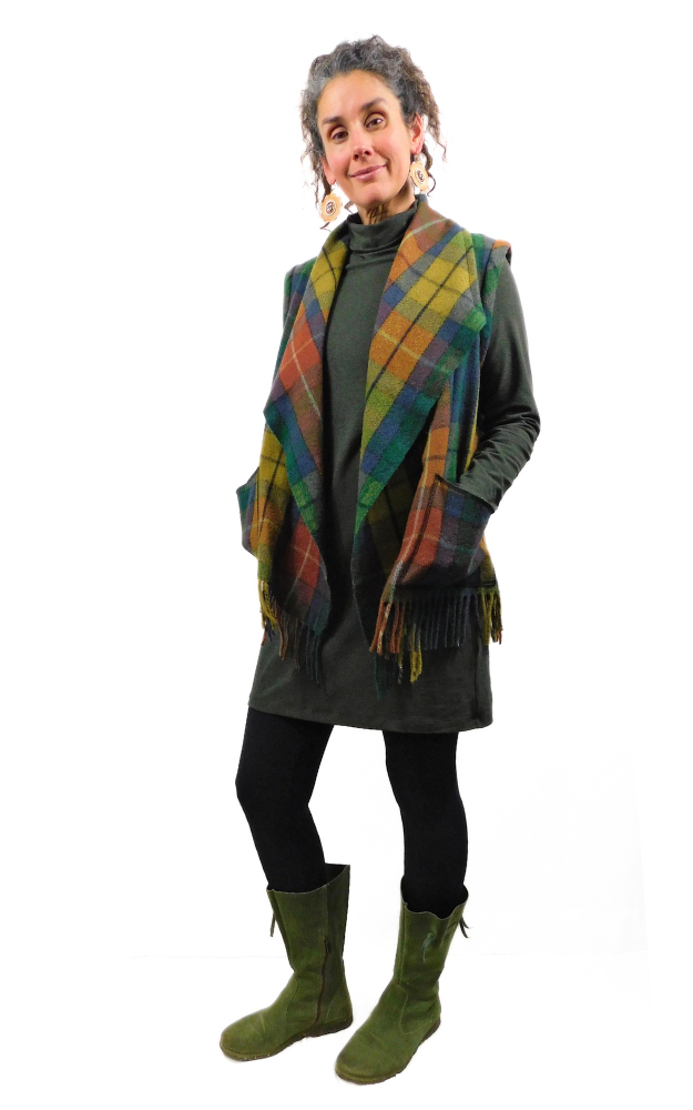 Woman wearing a colorful tartan vest, black pants, and green boots on a white background