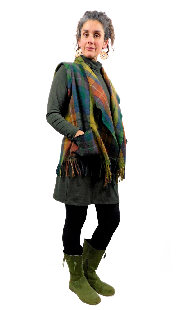 Woman wearing a tartan vest over a dark outfit on a white background