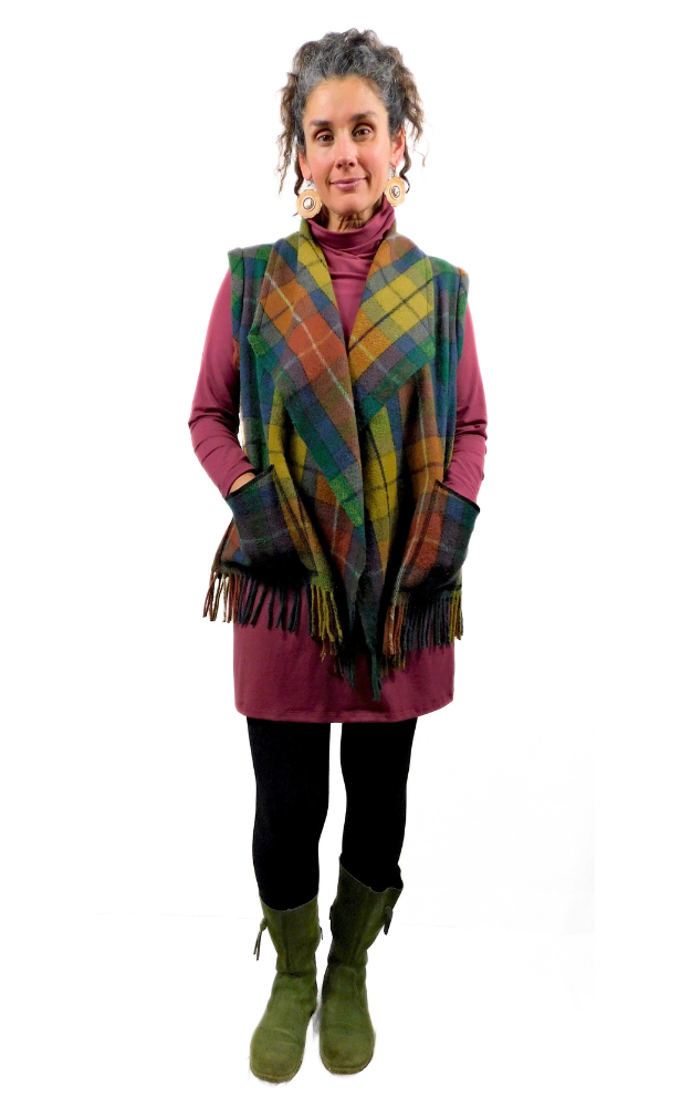 Woman wearing a colorful plaid vest over a pink outfit on a white background