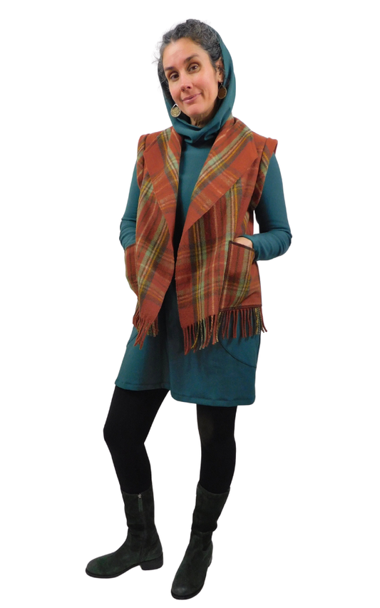 Woman wearing a plaid vest over a teal dress on a white background