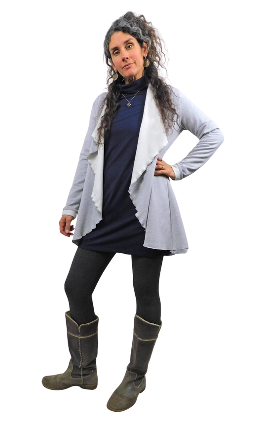 Woman wearing a gray cardigan, dark dress, black leggings, and gray boots on a white background