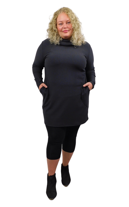 Woman wearing a black tunic with long sleeves and capri leggings on a white background