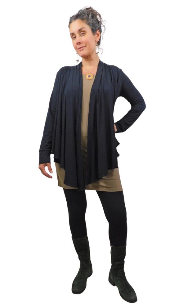 Woman wearing a black cardigan over a beige top with black pants and boots on a white background