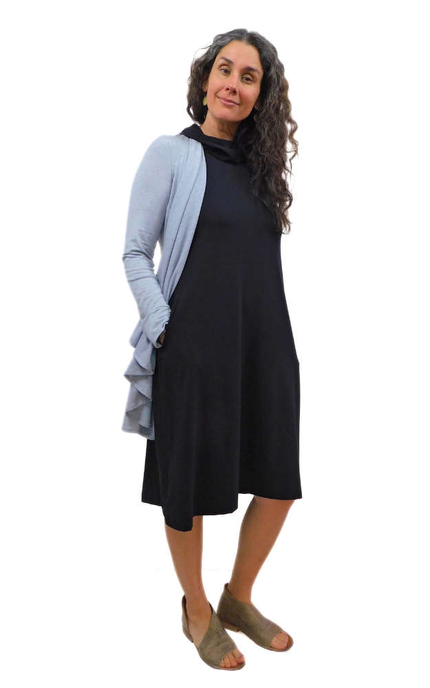Black capped sleeve wide long tunic dress with side pockets and large hood that can drape around the neck as a cowl. Garment is made from a 
High Twist Jersey knit w/Spandex, with a lovely stretch and drape. Model wears a wrap overtop the dress.