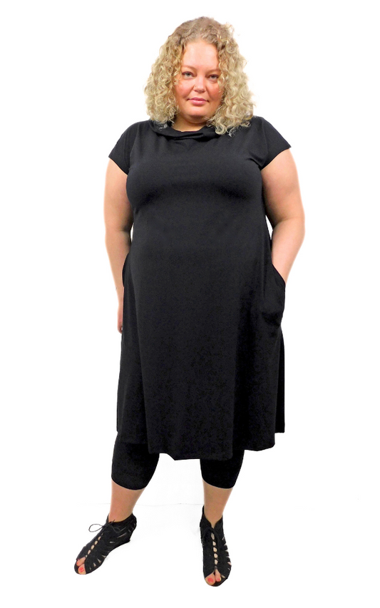 Model wears size 3XL black capped sleeve wide long tunic dress with side pockets and large hood that can drape around the neck as a cowl. 