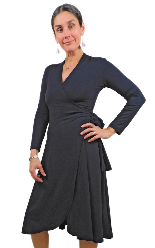 Woman body hand on hip wearing black wrap dress long sleeves tie belt below knee hem