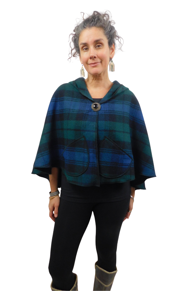 Woman wearing a blue and green and black tartan cape with front brooch and patch pockets, worn over black leggings