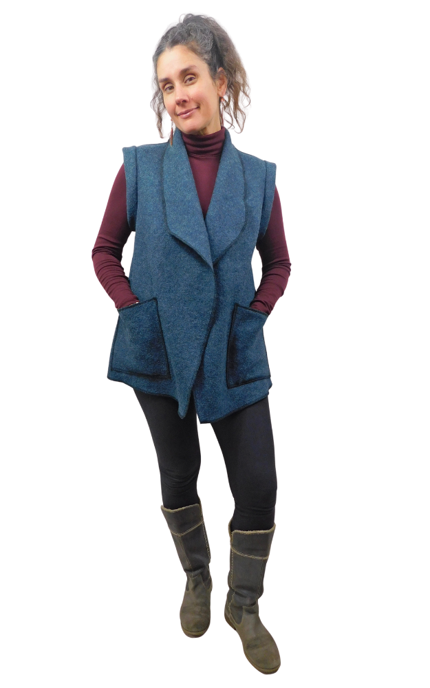 Woman wearing a  Blue colour Boiled Wool Vest with patch pockets over a wine colour sweater and black leggings and boots