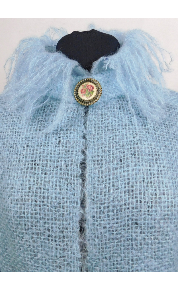 Light blue knitted jacket just showing fluffy collar with a decorative button on a white background