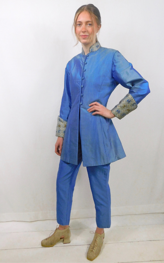 Person wearing a blue outfit with patterned cuffs on a white background