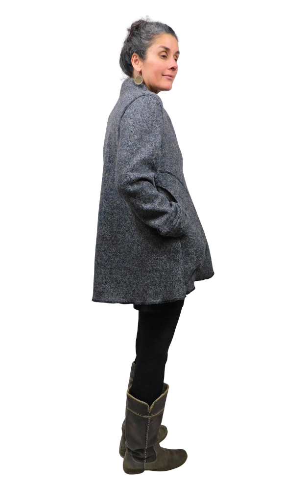 Side view of woman wearing charcoal wool coat with hands in pockets and black tights and grey boots
