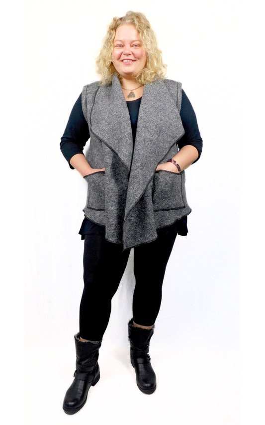 Woman wearing a Charcoal Colour Boiled Wool Vest with patch pockets over a black sweater and black leggings and boots