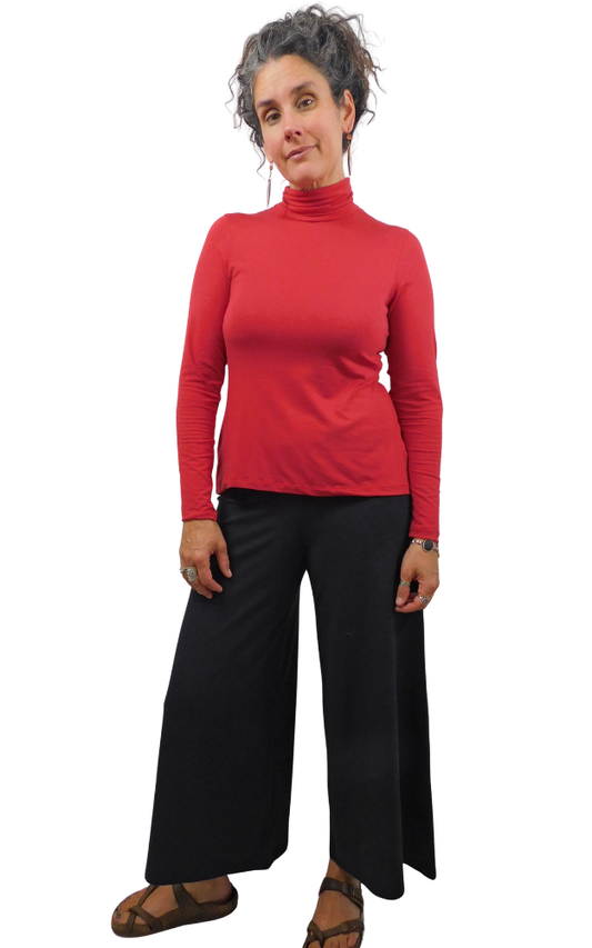 A woman modeling a bright red long-sleeve turtleneck top and black wide-leg pants against a plain white background.