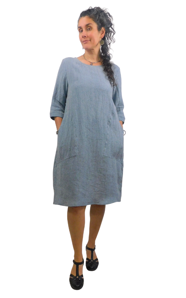 Woman wearing a striped blue and white dress standing against a white background