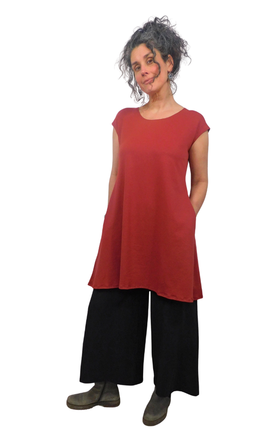 Woman wearing a red tunic and black pants on a white background