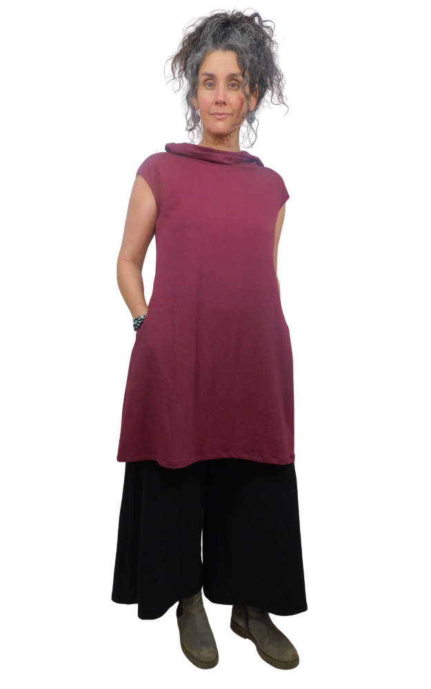 Woman wearing a maroon sleeveless top and black pants on a white background