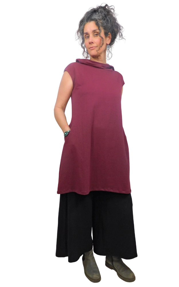 Woman wearing a maroon sleeveless top and black pants on a white background