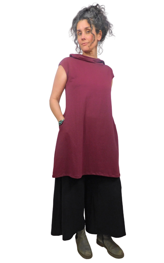 Woman wearing a maroon sleeveless top and black pants on a white background