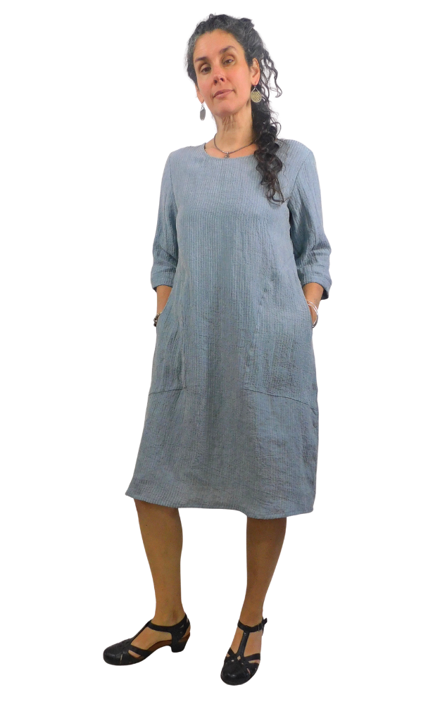 Woman wearing a striped blue and white dress standing against a white background