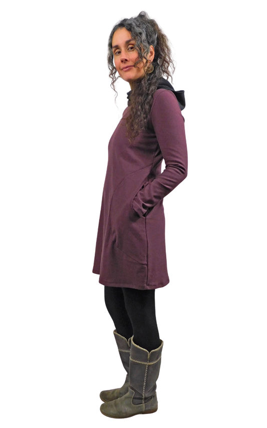 Woman wearing a wine colour coat and grey boots on a white background