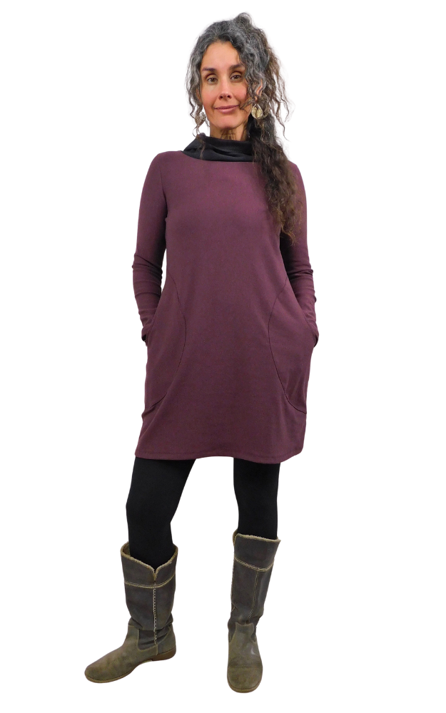Woman wearing a wine coloured tunic dress with hands in pocket and black cowl neck