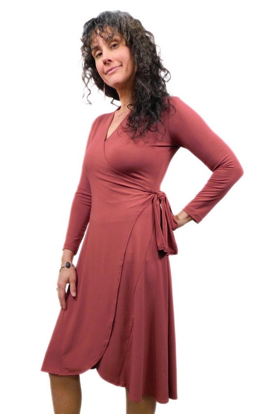 Woman standing sideways wearing wine coloured wrap dress long sleeves tie belt below knee hem