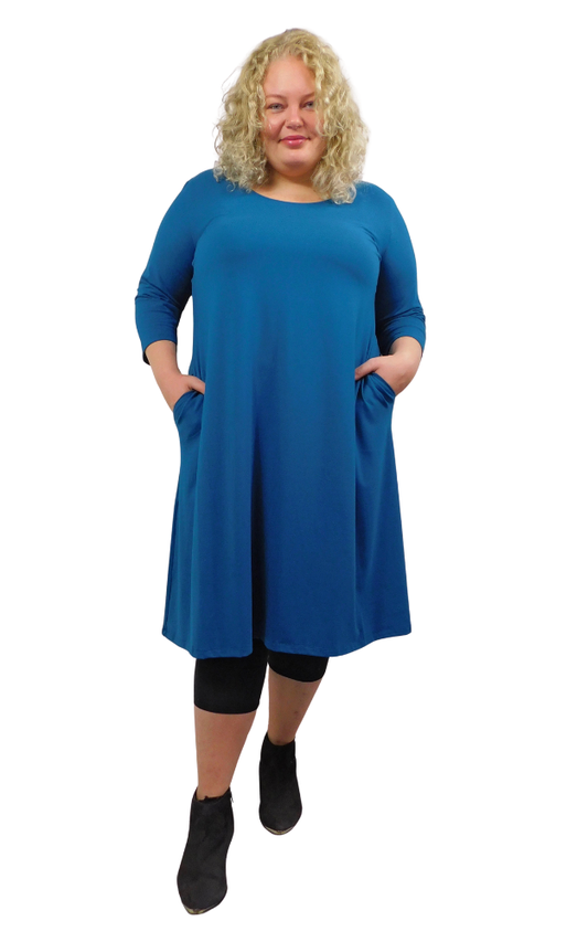 Woman wearing a blue dress with pockets on a white background