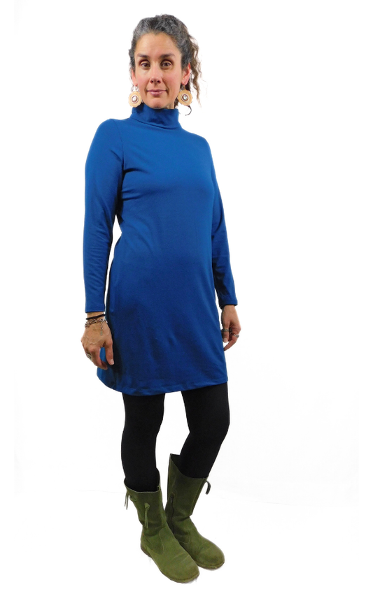 Woman wearing a blue turtleneck dress with green boots on a white background