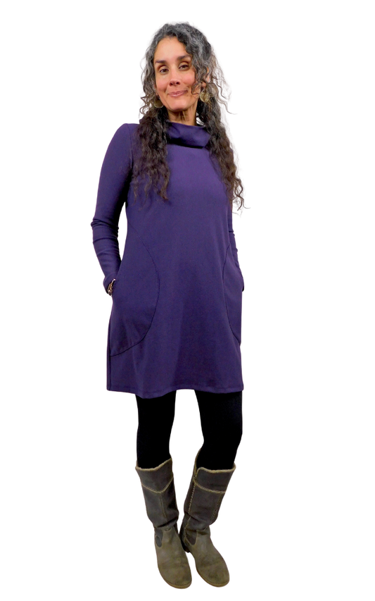 Woman wearing a purple tunic dress with long sleeves and pockets on a white background