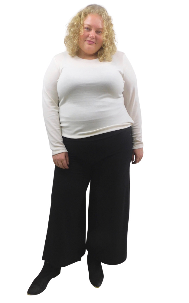 A woman modelling a white long-sleeve crewneck top and black wide-leg pants against a plain white background.