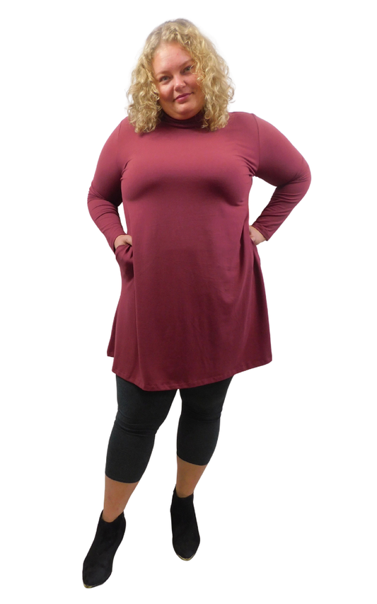 A woman modeling a long-sleeve, high-neck turtleneck tunic dress in wine styled with charcoal leggings