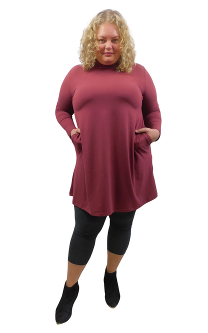 A woman modeling a long-sleeve, high-neck turtleneck tunic dress in a dusty rose wine color, styled with charcoal leggings.