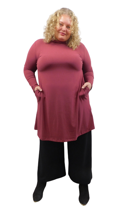 A woman modeling a long-sleeve, high-neck turtleneck tunic dress in wine colour  styled with wide black pants