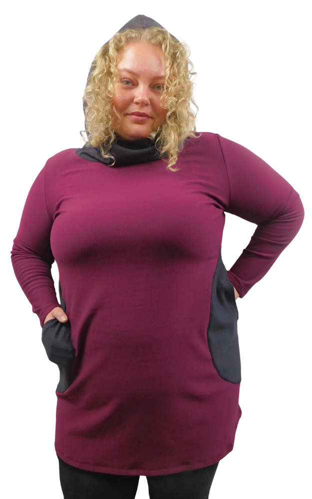 A woman modeling a hooded tunic dress in deep burgundy with contrasting dusty black front pockets, against a plain white background.